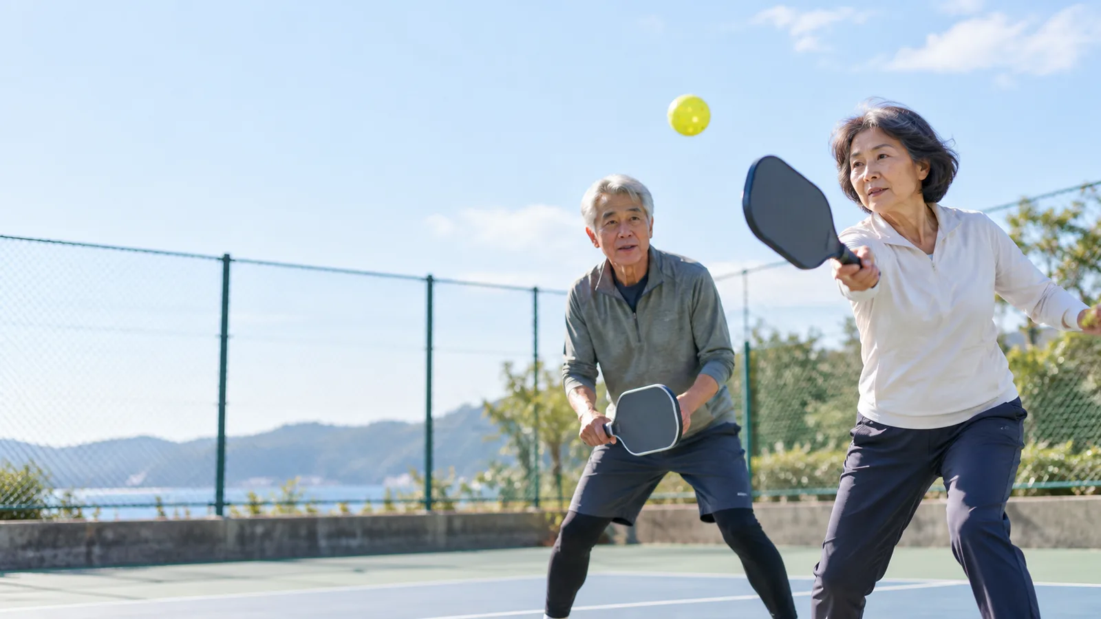 屋外のコートで、ピックルボールを楽しむ60代の夫婦